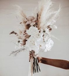 a person holding a bouquet with flowers and feathers