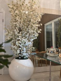 a white vase filled with flowers on top of a glass table