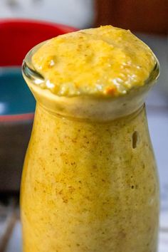 a glass jar filled with yellow liquid sitting on top of a table