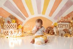 a baby sitting on the floor in front of a cake