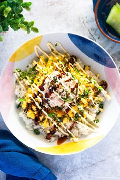 korean tuna mayo rice in a white bowl with chopsticks on the side and green vegetables next to it