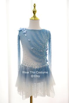 a blue and white dress on display in front of a window with the words wear this costume @ efy