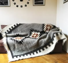 a living room with a couch covered in a blanket and pictures on the wall behind it