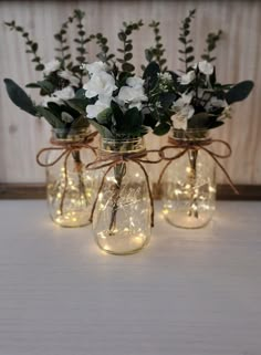 three mason jars filled with flowers and lights