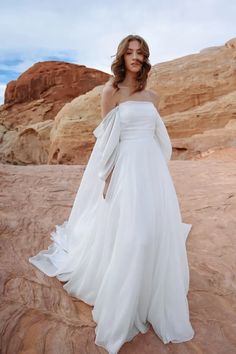 a woman in a white dress standing on rocks