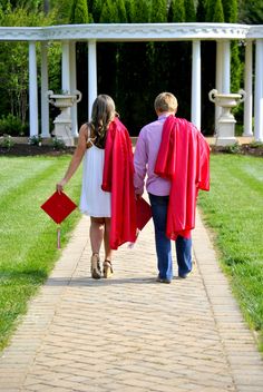 a man and woman in graduation gowns walking down a brick path with their backs to each other