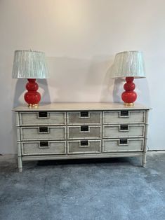 two lamps are on top of a dresser with drawers and drawers in front of it