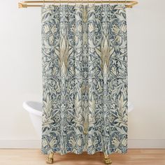 a blue and white shower curtain with an ornate design on it's side, in front of a bathtub