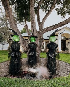 three witches standing in front of a tree with green lanterns on their heads and legs