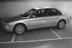 a silver car parked in a parking lot next to a wall with no people on it