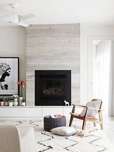 a living room with a fireplace, chair and pictures on the wall above it that says home's one new address