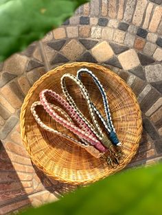 four bracelets sitting in a wicker basket on a stone floor next to green leaves