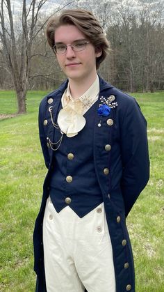 a young man dressed in period clothing standing on grass