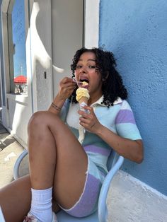 a woman sitting on a chair eating an ice cream sundae with her legs crossed