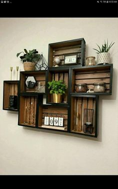 an assortment of shelves with plants and other items in them on the wall next to a white wall