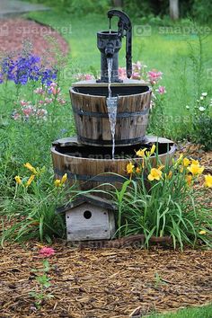 a water fountain in the middle of some flowers