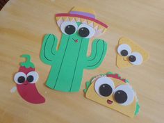 paper cut out of the shape of a cactus with eyes, nose and mouth sitting on top of a wooden table