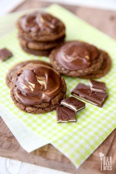 chocolate cookies with marshmallows on a green and white checkered napkin next to them