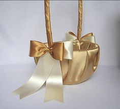 a gold and white basket with ribbon tied around the handle, on a white background