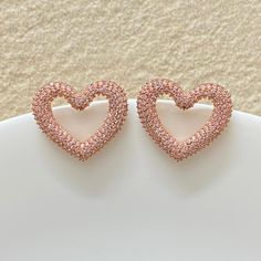 Pink diamond earrings featuring fancy pink stones in an pave setting in heart shape. Ideal to pair with your prom gowns or any special occasion drees. These pink diamond earrings surely elevate your look. Perfect gift for her. *𝐏𝐑𝐎𝐃𝐔𝐂𝐓 𝐃𝐄𝐓𝐀𝐈𝐋* * 𝐌𝐚𝐭𝐞𝐫𝐢𝐚𝐥: Brass * 𝐏𝐥𝐚𝐭𝐢𝐧𝐠: Rose Gold Plated * 𝐒𝐭𝐨𝐧���𝐞: AAA-quality CZ Diamond. *𝐃𝐈𝐌𝐄𝐍𝐒𝐈𝐎𝐍𝐒* * 𝐖𝐞𝐢𝐠𝐡𝐭: 5 gm each * 𝐋𝐞𝐧𝐠𝐭𝐡: 2.5 cm * 𝐖𝐢𝐝𝐭𝐡: 2.7 cm * 𝐂𝐥𝐨𝐬𝐮𝐫𝐞: Push Back 𝐕𝐢𝐬𝐢𝐭 𝐎𝐮𝐫 𝐅𝐀? Pink Diamond Earrings, Bride Wedding Gift, Earrings Luxury, Pink Stones, Pink Bride, Wedding Gifts For Bride, Cz Earrings, Pave Setting, Cz Diamond