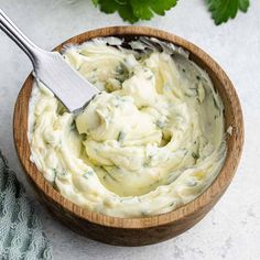 a wooden bowl filled with mashed potatoes and parsley