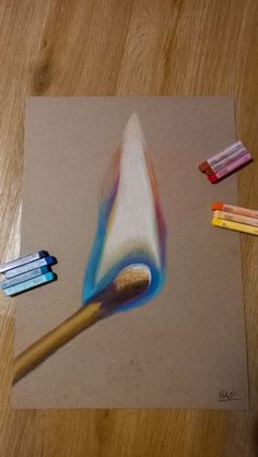 colored pencils are laying on top of a piece of paper next to a brush