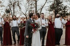 a bride and groom kissing in front of their wedding party