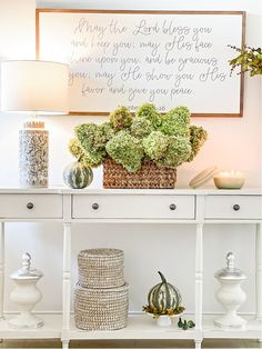 a white table topped with vases filled with flowers and greenery next to a framed quote