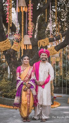 two people standing next to each other in front of a tree with decorations on it