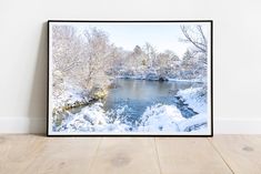 a framed photograph of a snowy river in the middle of a wood floored room