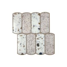 six pieces of white and black marble with speckles on the edges, set against a white background