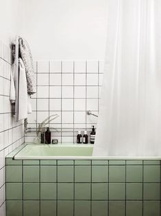 a bathroom with green tiles and white walls, including a bathtub in the corner