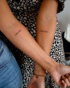 two people holding hands with tattoos on their arms and the words i love you written on them