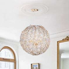 a living room with a couch, mirror and chandelier hanging from the ceiling