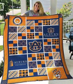 a woman is holding up a quilt that has auburn on it and the words auburn in blue