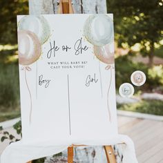 an easel with balloons and confetti on it for a baby's first birthday