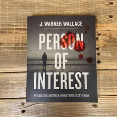 the book person of interest by j warnner wallace is laying on a wooden surface