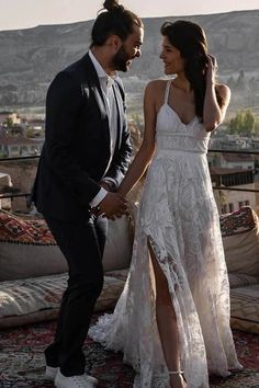 a man and woman standing next to each other in front of a couch with the city behind them