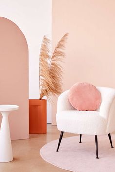 a white chair sitting on top of a rug next to a table and potted plant