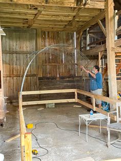 a man is working on a large metal object in an unfinished room with wood walls