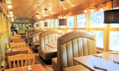 the interior of a restaurant with wooden tables and chairs, windows, and yellow walls