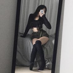 a woman taking a selfie in front of a mirror with her legs spread out