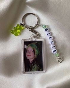 a keychain with a photo of a person wearing green hair and beads on it