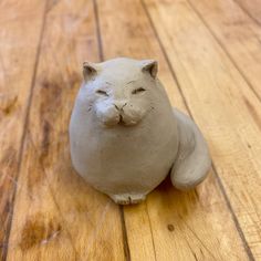 a ceramic cat sitting on top of a wooden floor