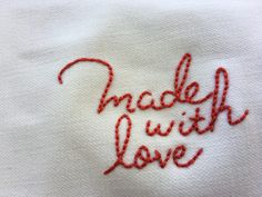 embroidered cloth with the words made with love written in red thread on white linens