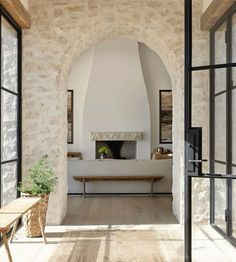 an open door leading to a living room with stone walls and arched doorways that lead into the dining area