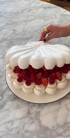 someone decorating a cake with strawberries on it