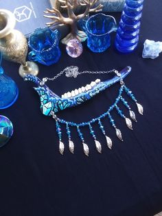 This is a Beautiful Painted, Blue and Purple Crystal Deer Jawbone Necklace! The Colors Here Are Just Fantastic! The Painted crystals Are a Light Blue Color And The Backdrop is Purple! A few rhinestones as well. Hanging from the bottom is a Bib of Glass beads! All 6 Teeth Are in perfect condition. The Whole Jaw Bone is 9 inches long. Also coated with polyurethane for the beautiful shine. The Chain is 20 inches long. All Items Ship Within 1-3 Days via USPS First Class Service. Shipping on This Bon Artistic Blue Necklaces For Festivals, Artistic Blue Necklace For Festivals, Handmade Blue Fantasy Jewelry, Hand Painted Blue Spiritual Necklace, Artistic Blue Jewelry For Festivals, Oddity Decor, Real Bone Jewelry, Animal Bone Jewelry, Wiccan Necklace