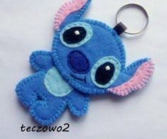 a blue stuffed animal keychain with black eyes and a pink nose is on a white surface