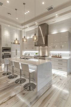 a large kitchen with white cabinets and counter tops, along with bar stools in front of the island